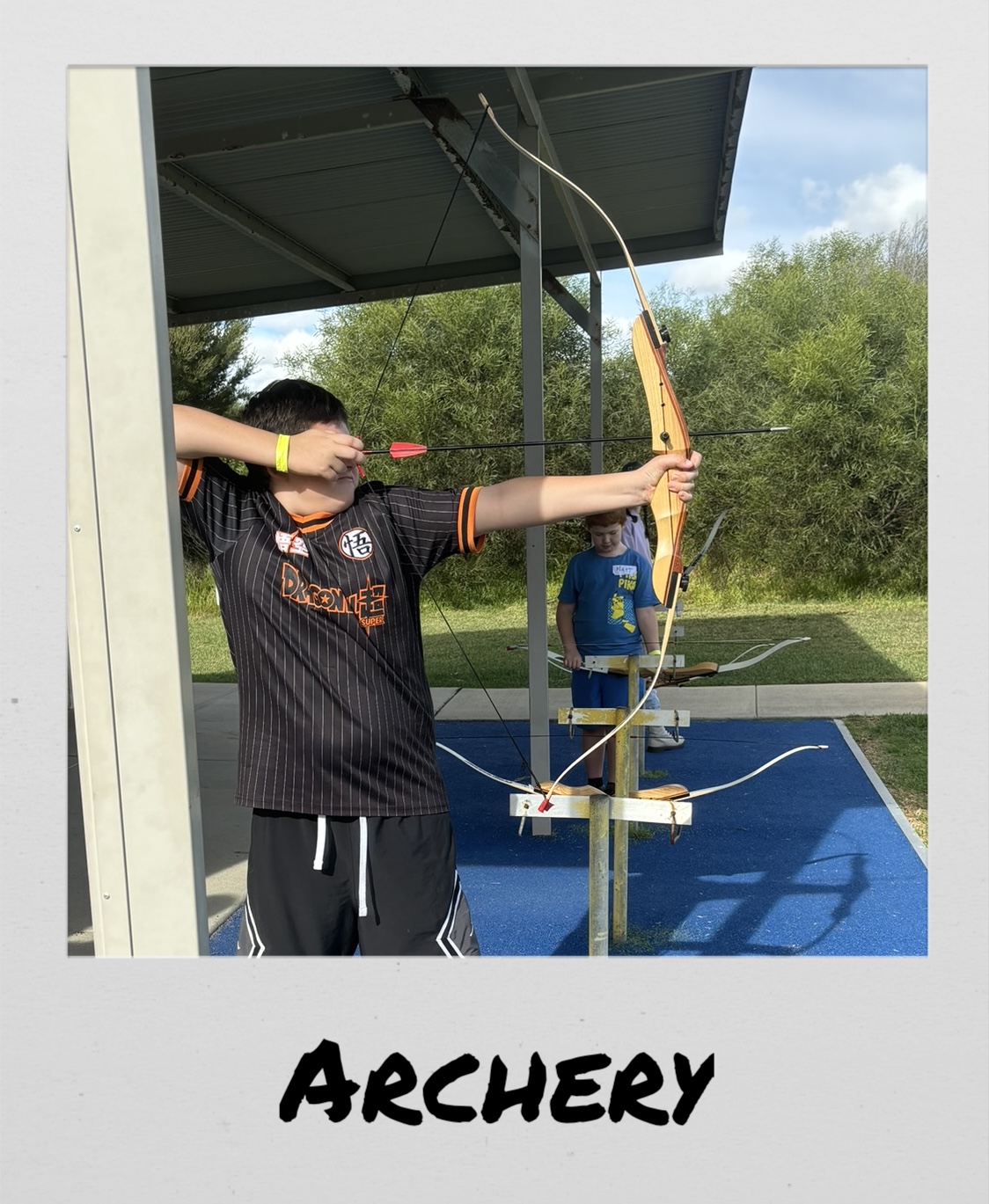 Polaroid image of a boy shooting a bow, titled “Archery”