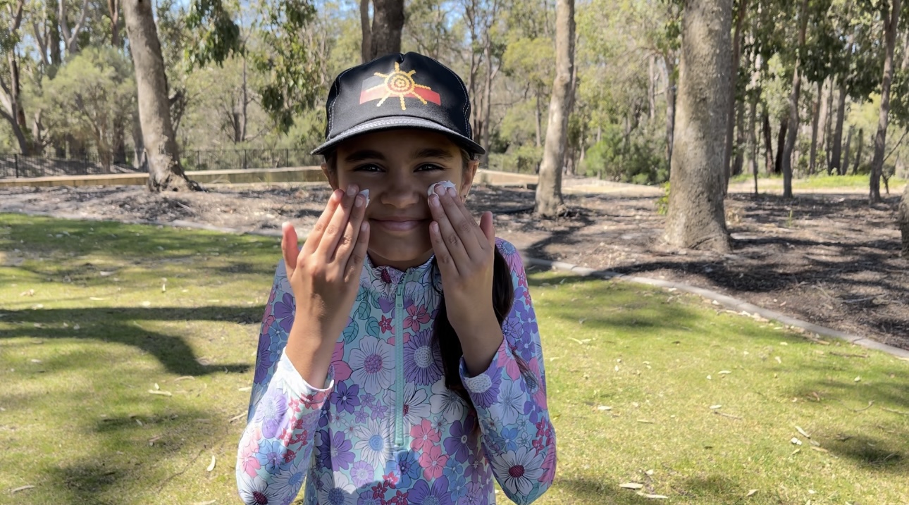 child applying sunscreen